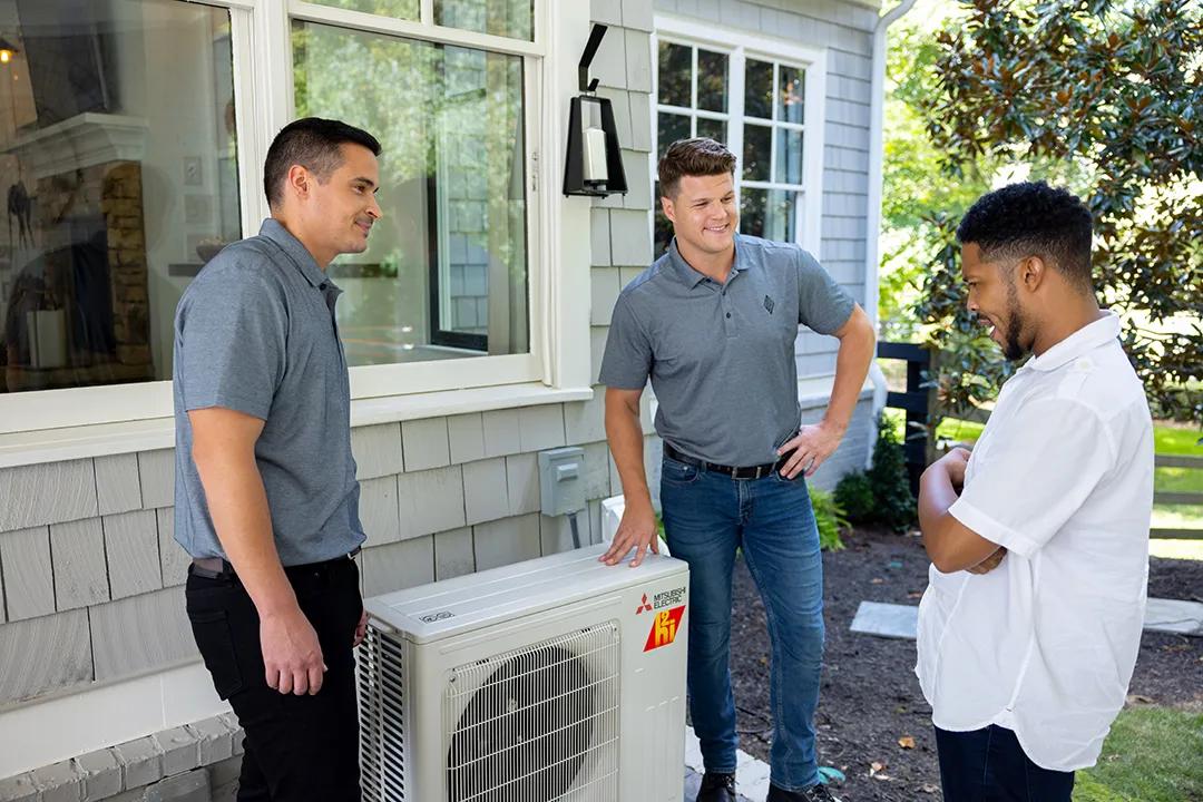 Contractors demonstrating newly installed heat pump to homeowner