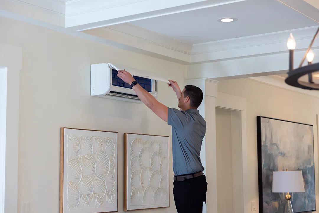 HVAC technician servicing wall-mounted indoor unit